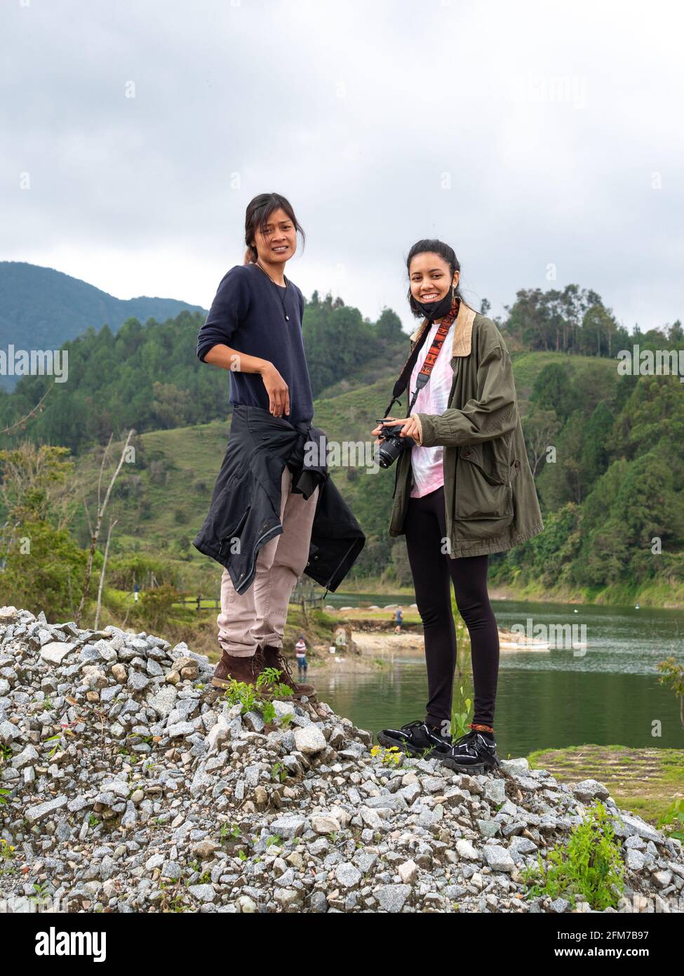 Guatape, Antioquia, Colombia - 4 aprile 2021: Giovani donne ispaniche e asiatiche in una montagna di pietra vicino al fiume Foto Stock