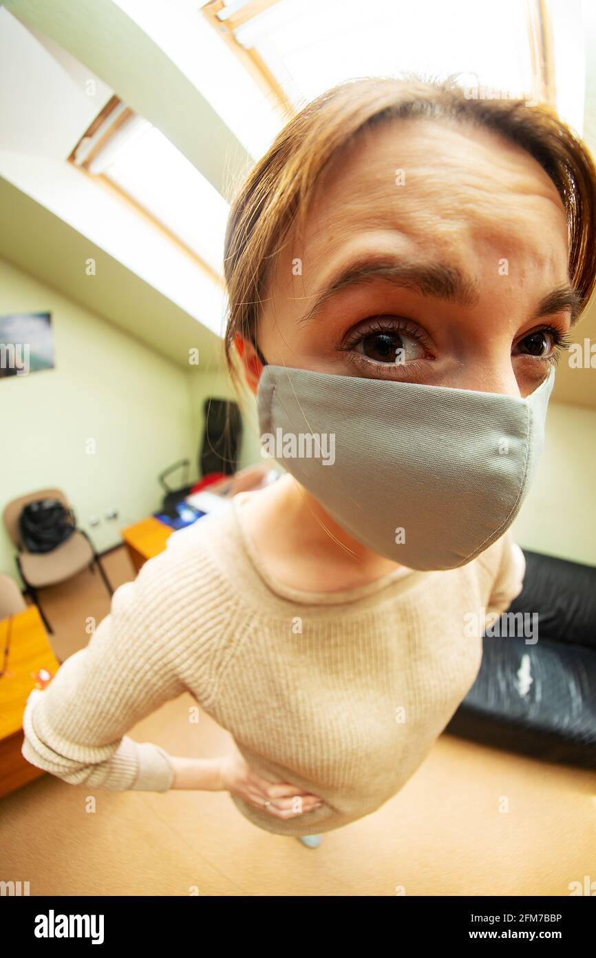 ritratto di un uomo con occhiali e una maschera medica, un uomo che guarda nella fotocamera fish-eye obiettivo, divertente distorsione di proporzioni primo piano, animatori Foto Stock