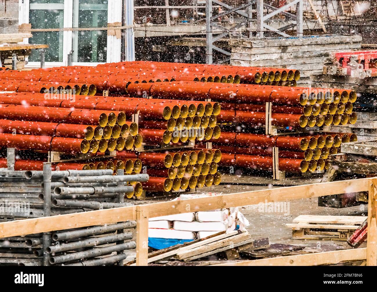 Cumulo di tubi termoplastici in polietilene industriale rotondi stoccaggio all'aperto in un cantiere con neve in inverno freddo. Foto Stock