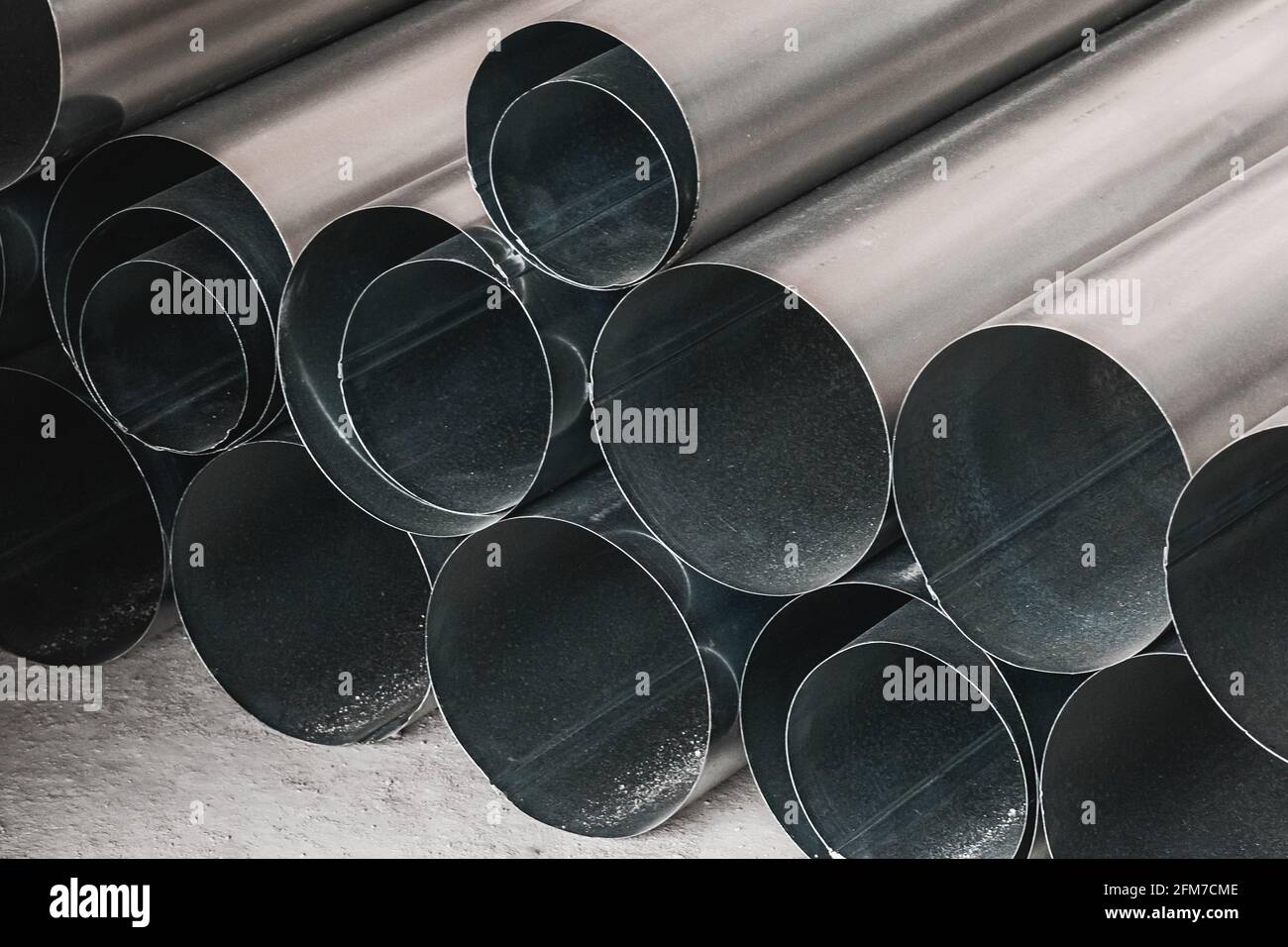 Pila di tubi di metallo rotondi ad un luogo di costruzione. Stoccaggio tubi in acciaio materiali industriali in magazzino. Foto Stock