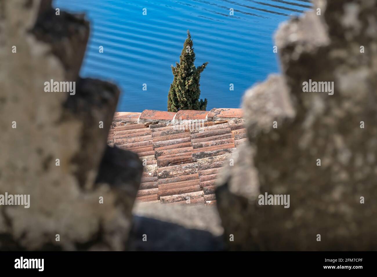 Vista attraverso l'apertura della vecchia parete al Tetto della vecchia casa e l'albero vicino al lago Lugano nella città svizzera di Morcote Foto Stock