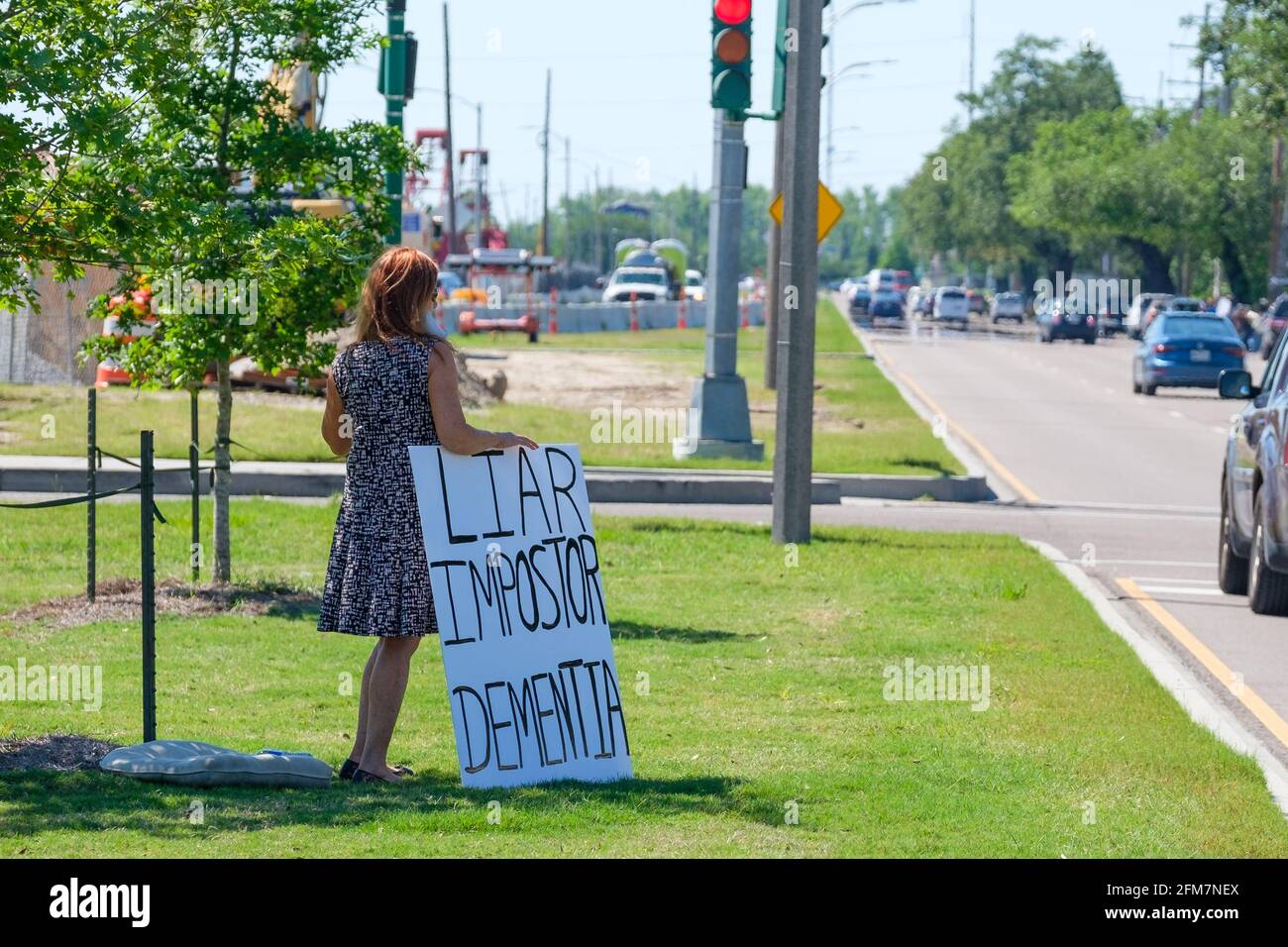 NEW ORLEANS, LA, USA - 6 MAGGIO 2021: Dimostratore Lone Anti Biden con segno sulla mediana in attesa di motocicletta presidenziale su Claiborne Avenue Foto Stock