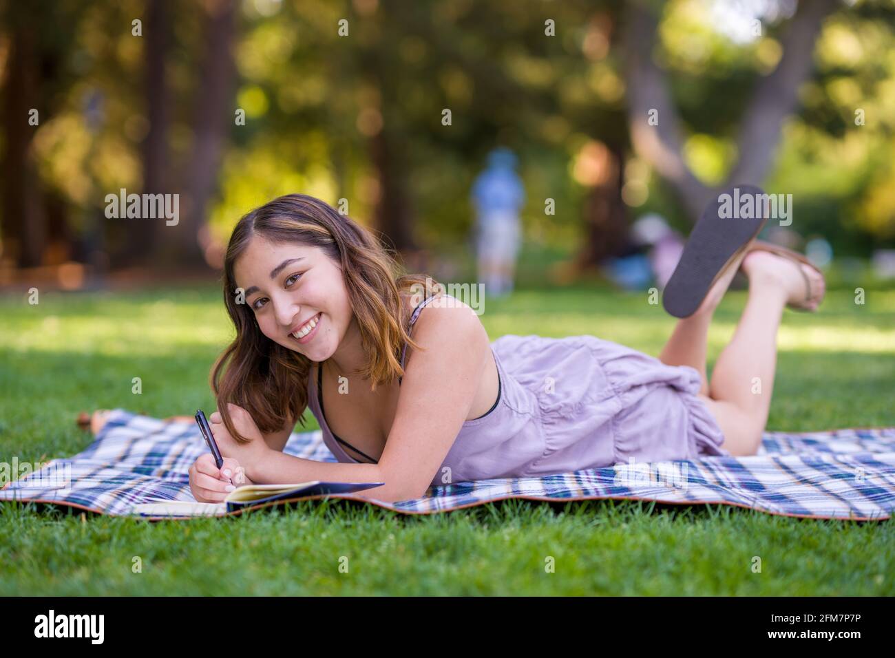 Petite giovane donna asiatica studente scrittura nel Parco Foto Stock