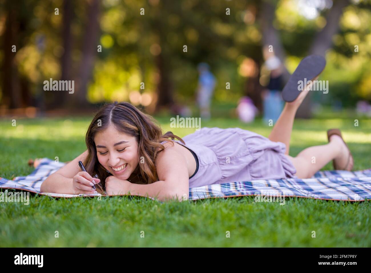 Petite giovane donna asiatica studente scrittura nel Parco Foto Stock