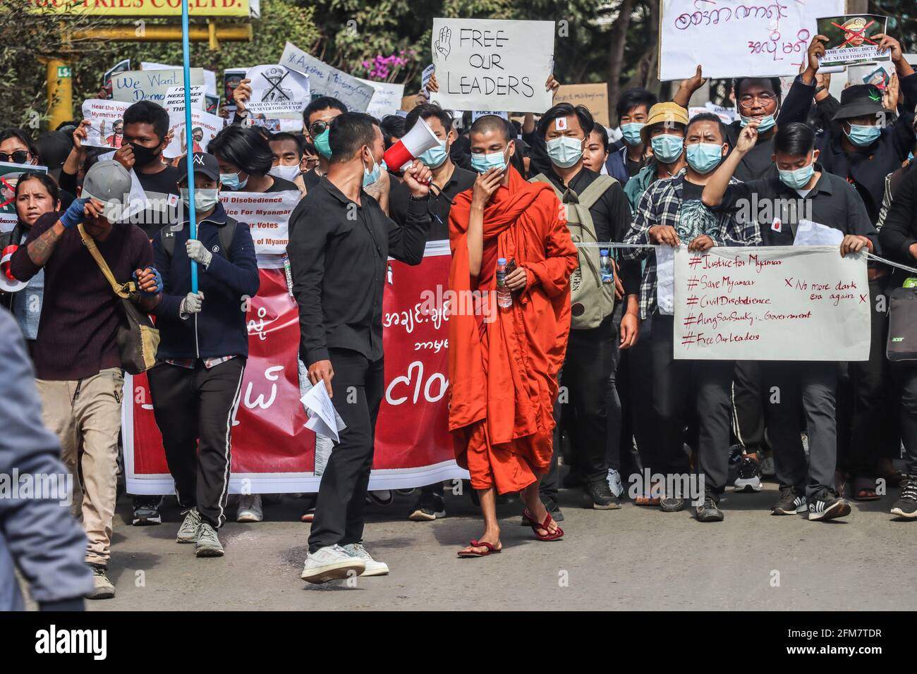 Lashio, Stato dello Shan del Nord, Myanmar. 17 Marzo 2021. Un monaco insieme ai dimostranti militari marciano con cartelli e striscioni che chiedono di liberare Aung San Suu Kyi durante una manifestazione contro il colpo di stato militare.UNA folla massiccia scese per le strade di Lashio per protestare contro il colpo di stato militare e chiese il rilascio di Aung San Suu Kyi. L'esercito del Myanmar ha arrestato il consigliere di Stato del Myanmar Aung San Suu Kyi il 01 febbraio 2021 e ha dichiarato uno stato di emergenza mentre coglie il potere nel paese per un anno dopo aver perso l'elezione contro la Lega nazionale per la democrazia (credito Imag Foto Stock