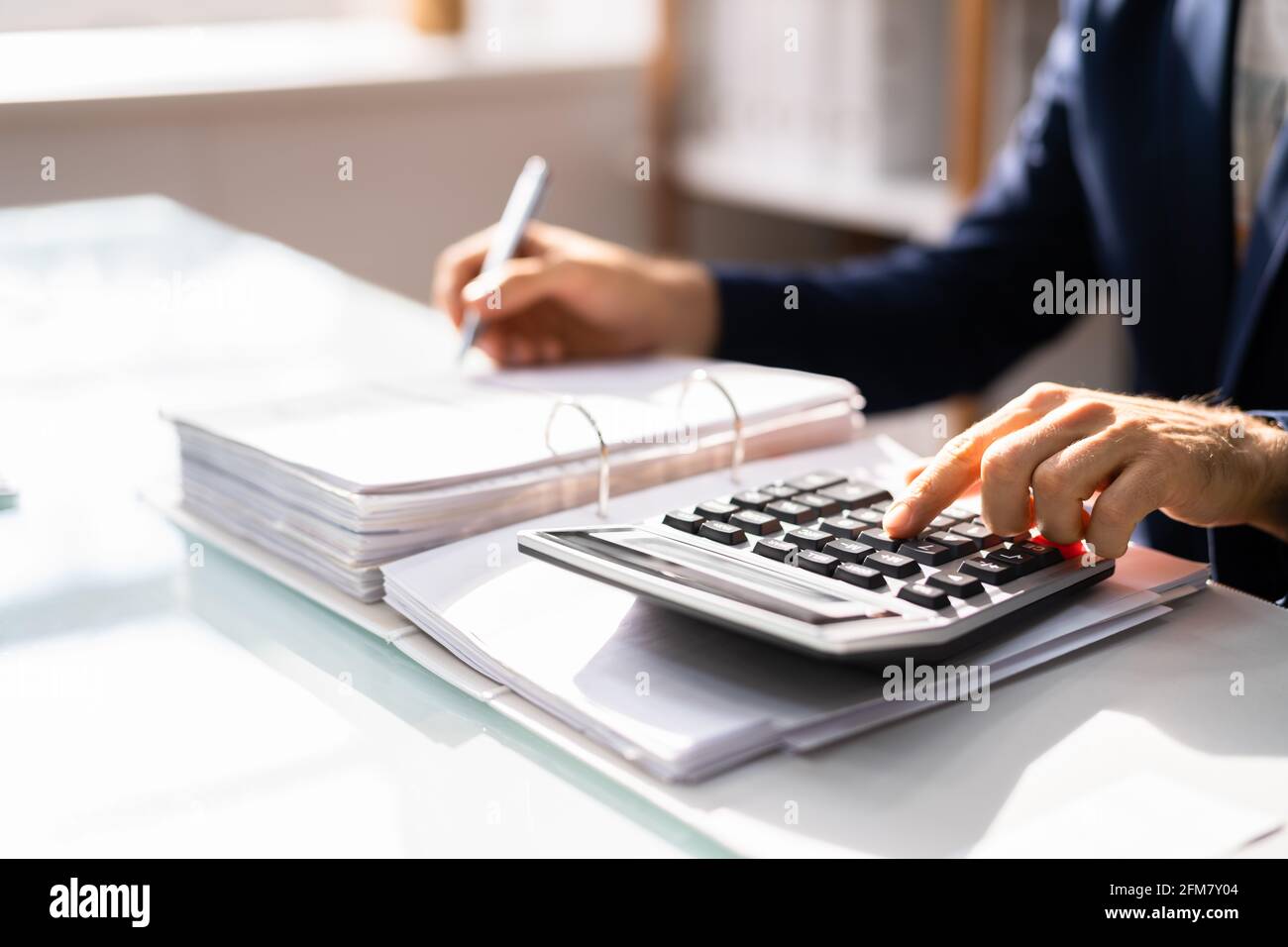 Uomo contabile che usa il calcolatore fiscale sulle fatture Foto Stock
