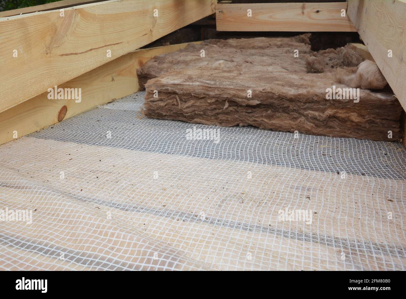 Isolamento del tetto: Un primo piano di lana minerale del tetto, isolamento di lana di vetro su una barriera di vapore, membrana tra i travetti di legno del soffitto. Foto Stock