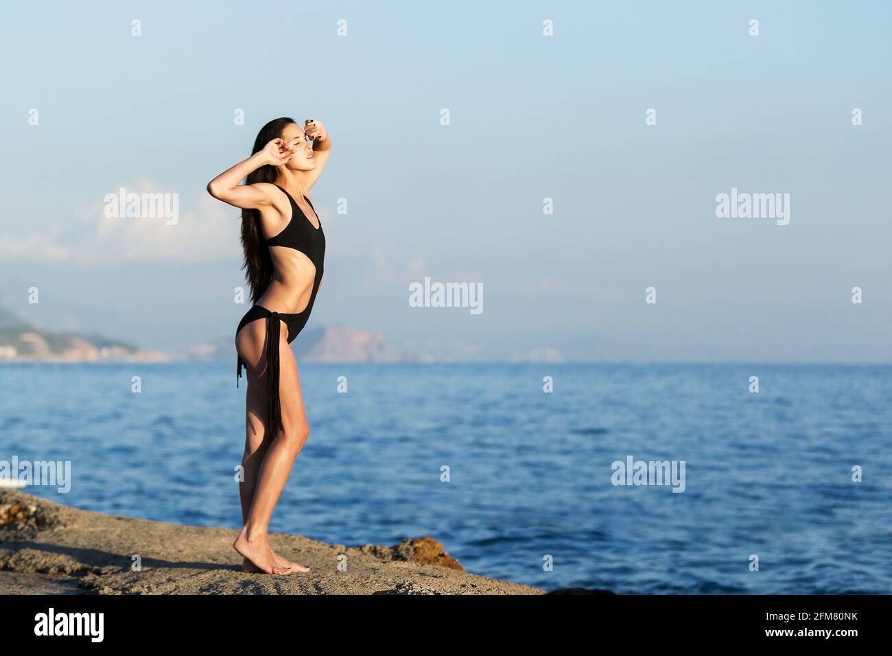 bella donna piccola abbronzata sulla spiaggia del tramonto Foto Stock