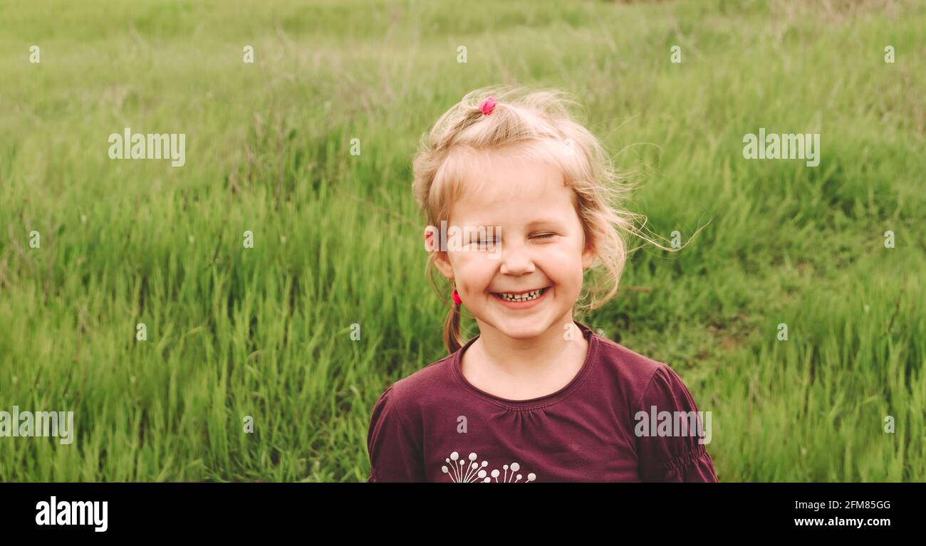 Ritratto dei bambini in natura. Spazio di copia. Bella ragazza bionda di 4 anni. Il bambino sorride guardando la macchina fotografica. Foto Stock