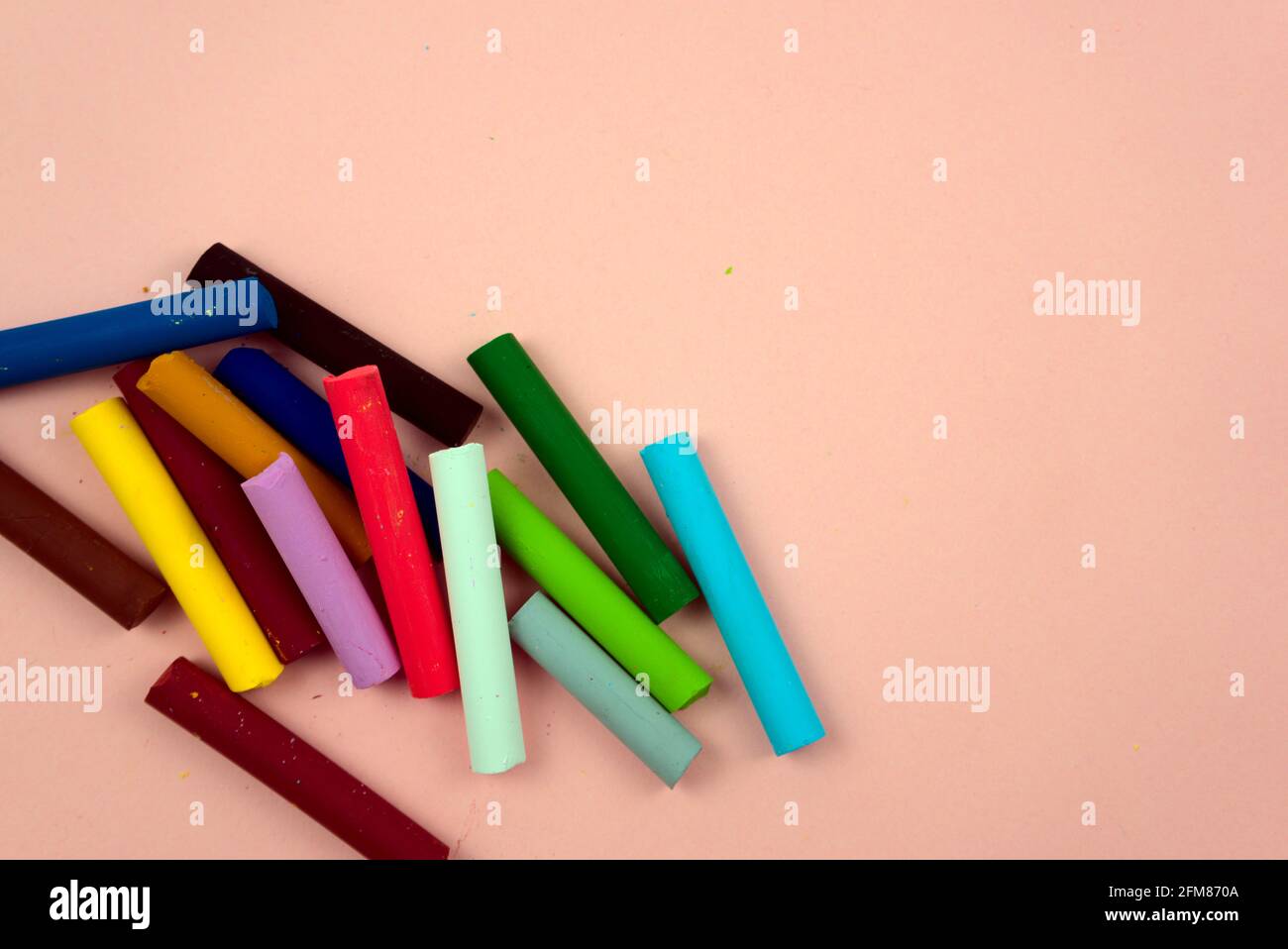 Colorati pastelli, varietà di gesso colorato piatto adagia su sfondo rosa pastello. Tavolozza dei colori degli artisti, forniture scolastiche, ricreazione, disegno d'arte. Foto Stock