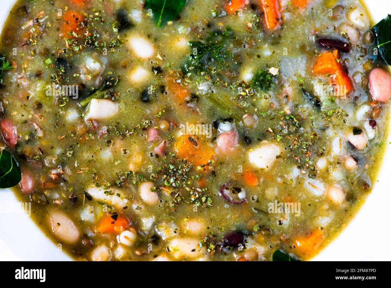 Densa zuppa di legumi toscani di tre tipi di fagioli, semole di grano e verdure, sano pasto vegetariano o vegano, primo piano. Foto Stock
