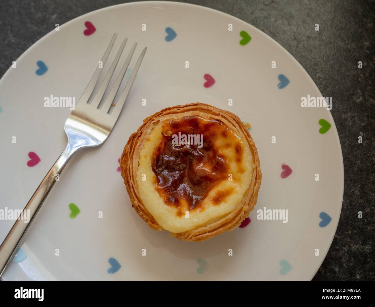 Tradizionale crostata di crema pastello de nata, colpo dall'alto su un piatto con forchetta. Foto Stock
