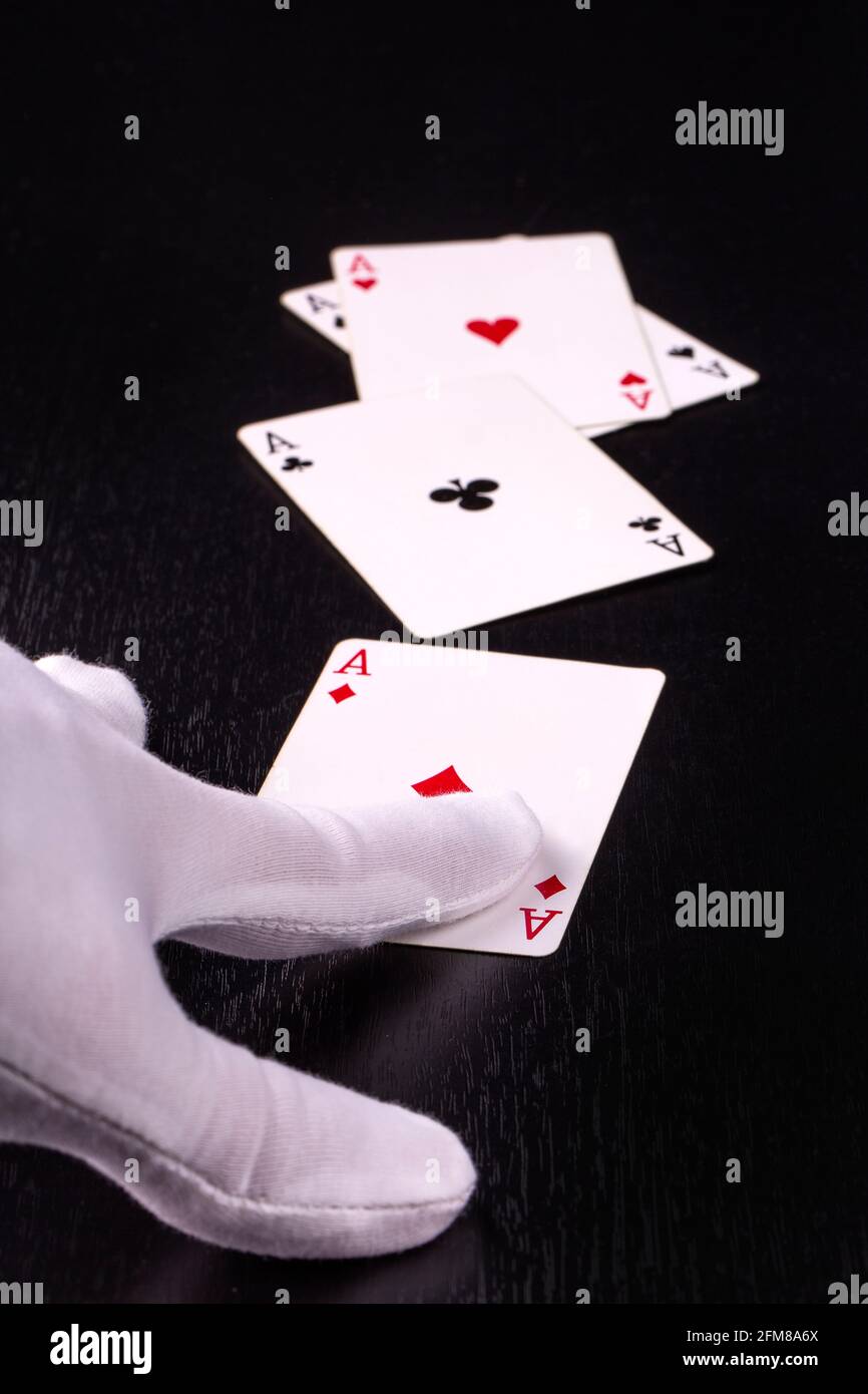 mano di primo piano del concessionario in guanti bianchi in una casino che consegna le carte su uno sfondo scuro Foto Stock