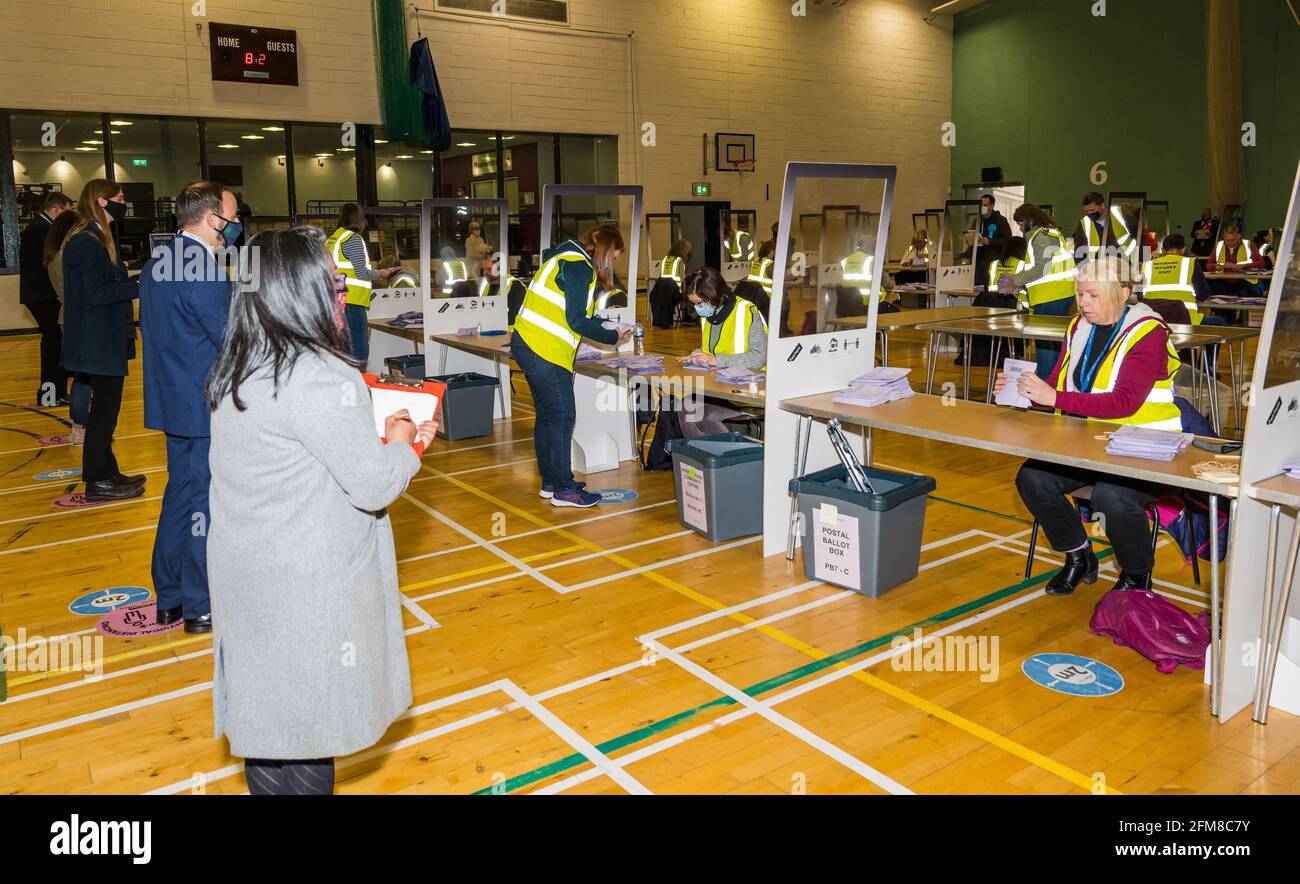 Centro sportivo Meadowmill, East Lothian, Scozia, Regno Unito. 7 maggio 2021. Le elezioni del parlamento scozzese contano per la circoscrizione della Lothian orientale: Il personale di funzionario che ritorna ordina le schede elettorali e conta i voti, mentre gli agenti candidati guardano socialmente distanziati Foto Stock