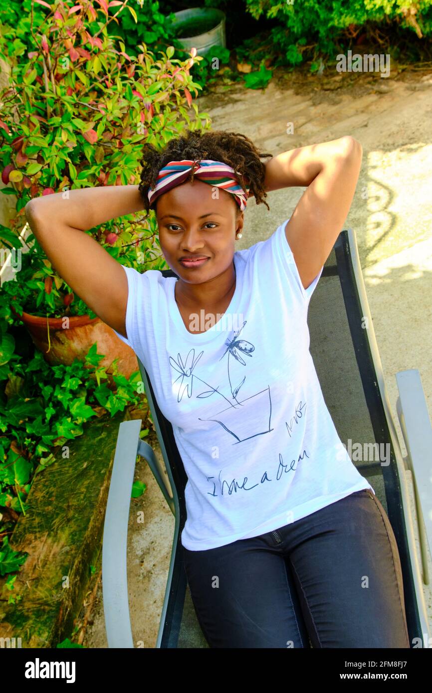 Giovane donna africana con uno stile fresco capelli e una t-shirt in posa all'aperto. Foto Stock