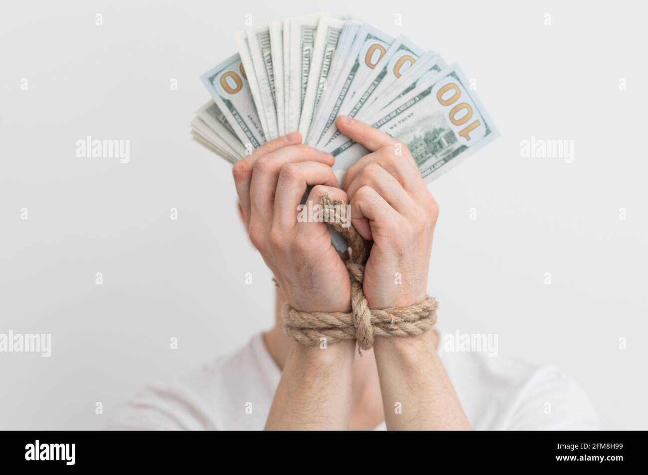 un uomo con le mani legate tenendo dollari, dipendenza dal denaro, rimborsi, arretrati di credito Foto Stock