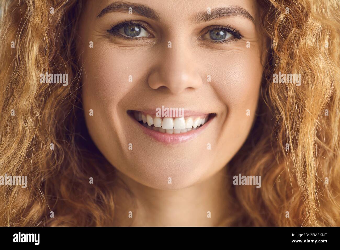 Ritratto closeup estremo di una donna felice con capelli ondulati e un sorriso bianco amichevole Foto Stock