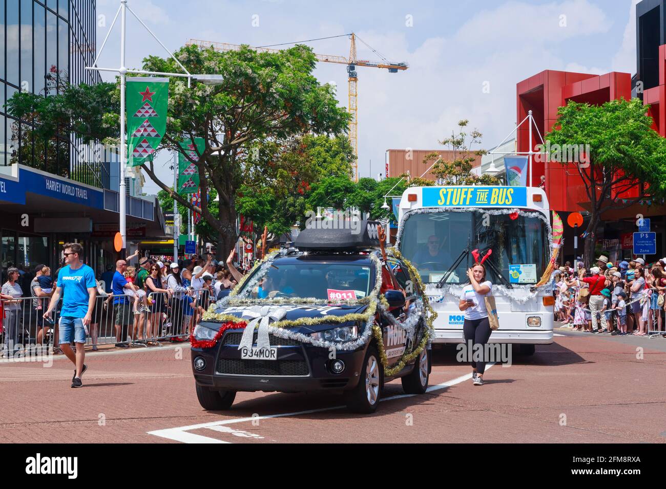 Una parata di Natale nel centro di Tauranga, Nuova Zelanda. Un'auto e un autobus, entrambi decorati da una stazione radio locale, che guidano da una folla Foto Stock