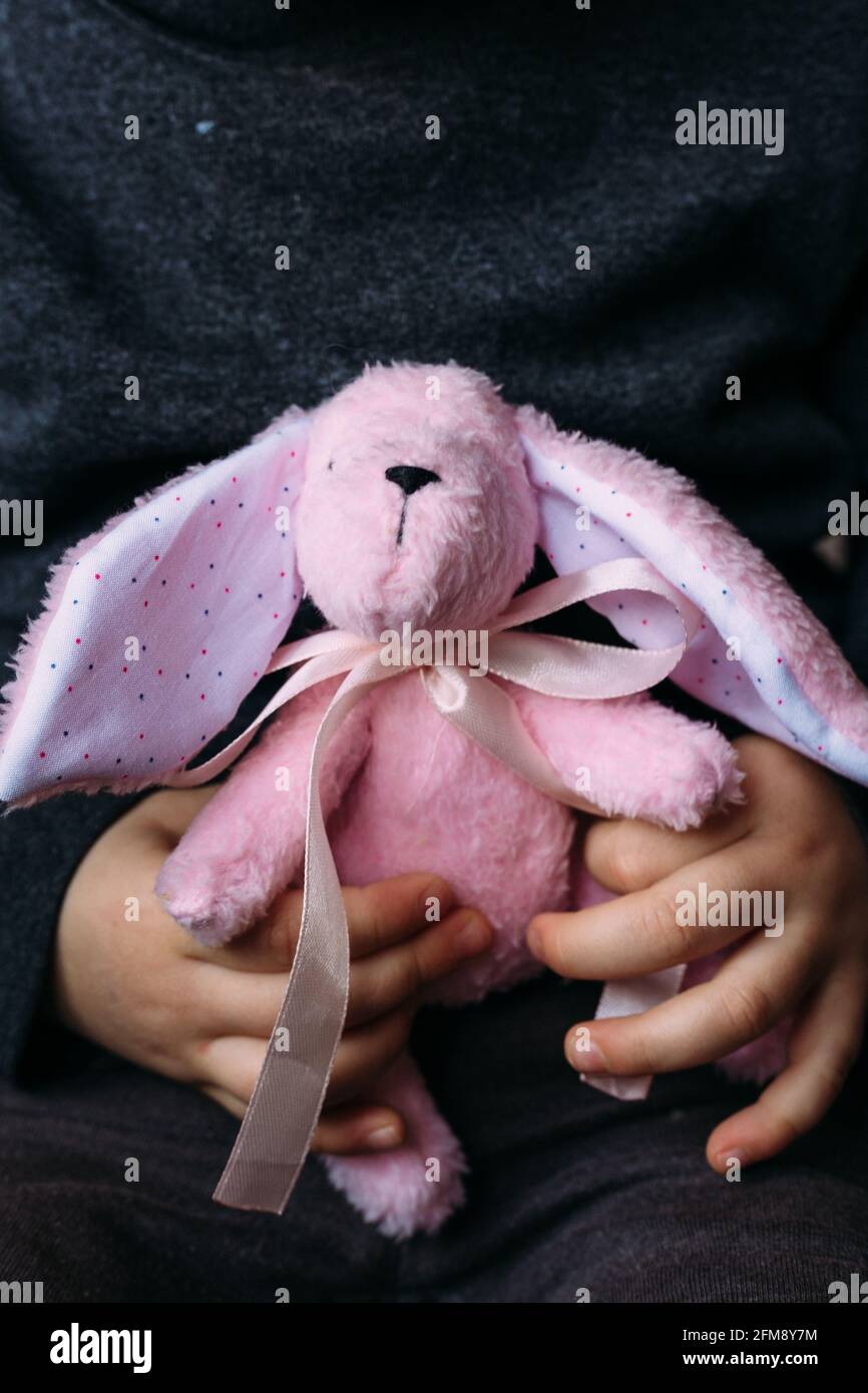Le mani dei bambini stanno tenendo un piccolo giocattolo morbido di coniglio.  Pubblicità sociale Foto stock - Alamy