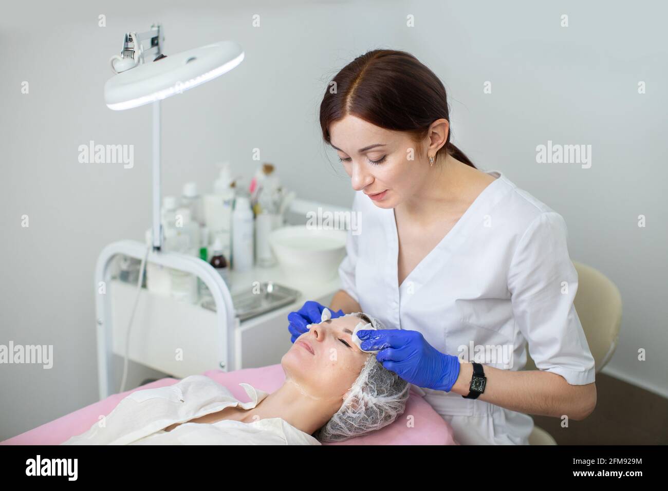 Giovane medico estetista di 35 anni in guanti di gomma, pulisce la pelle  della giovane donna con tovaglioli e spugne. Concetto di pelle perfetto,  pulizia, trattamento spa Foto stock - Alamy