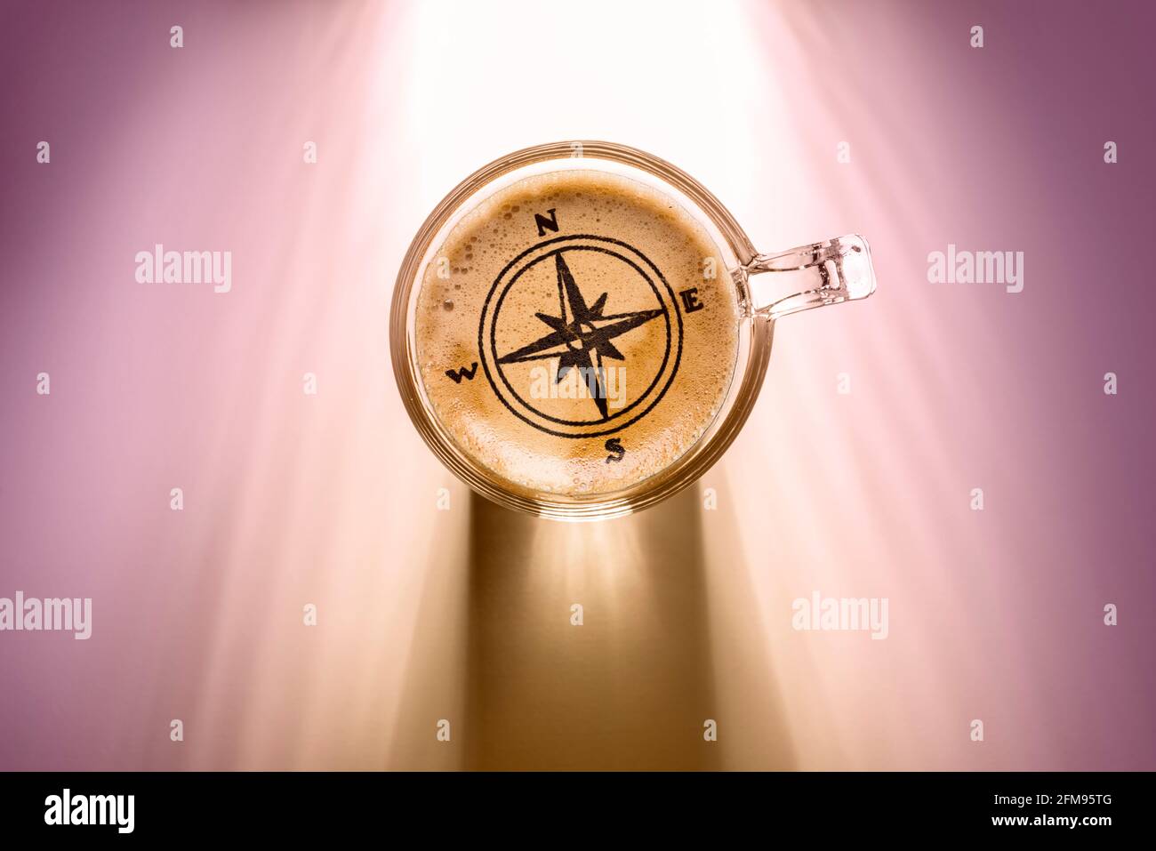 tazza da caffè con simbolo bussola, vista dall'alto sullo sfondo con luce solare. Foto Stock