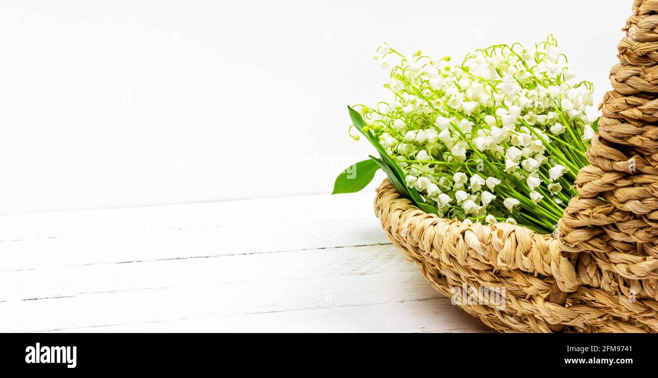 bouquet di giglio bianco della valle fiori in cesto su sfondo bianco in legno con spazio per la copia Foto Stock