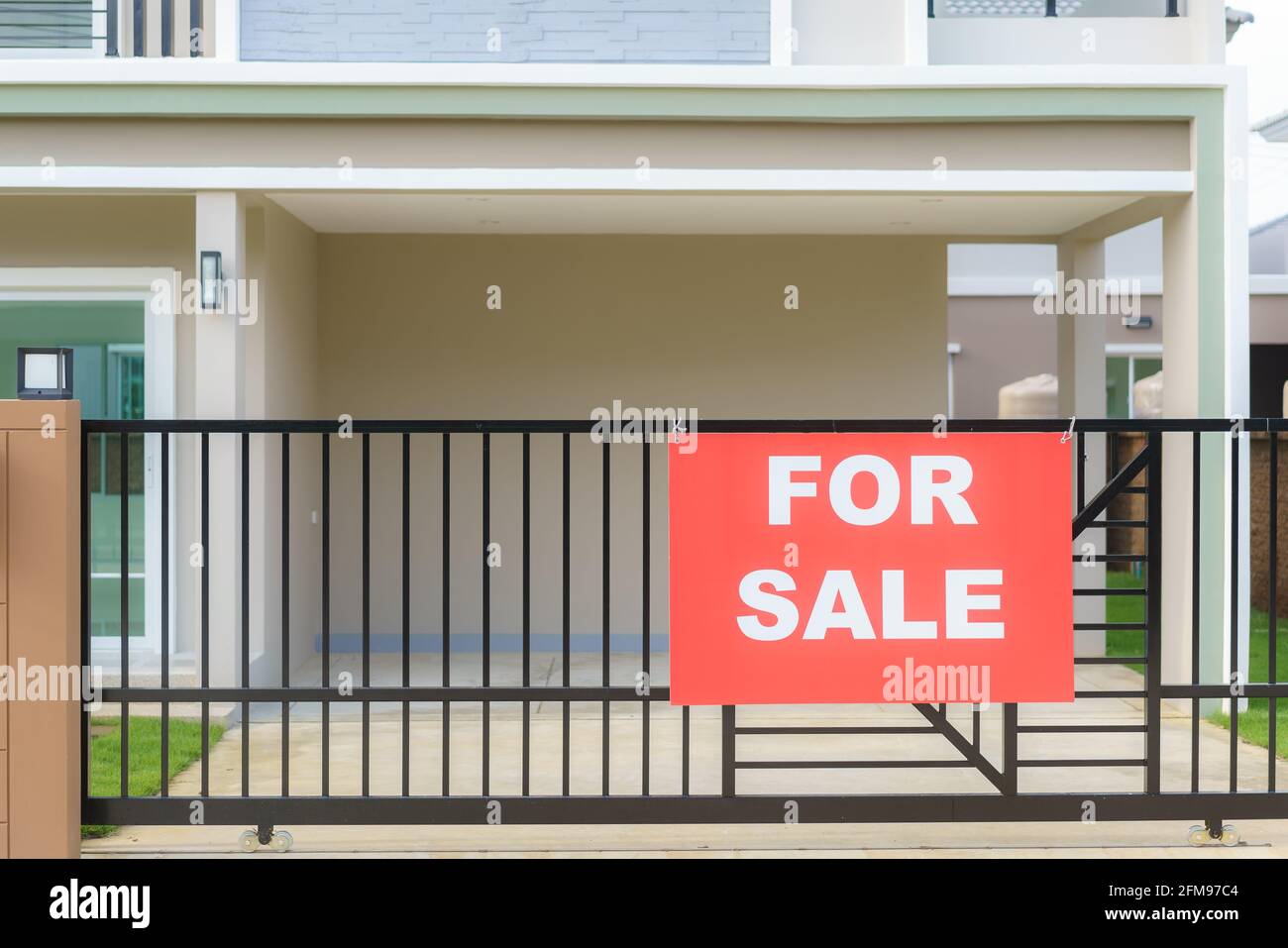 Cartello vendita casa appeso alla recinzione della porta della casa per annunciare agli interessati di contattare. Foto Stock