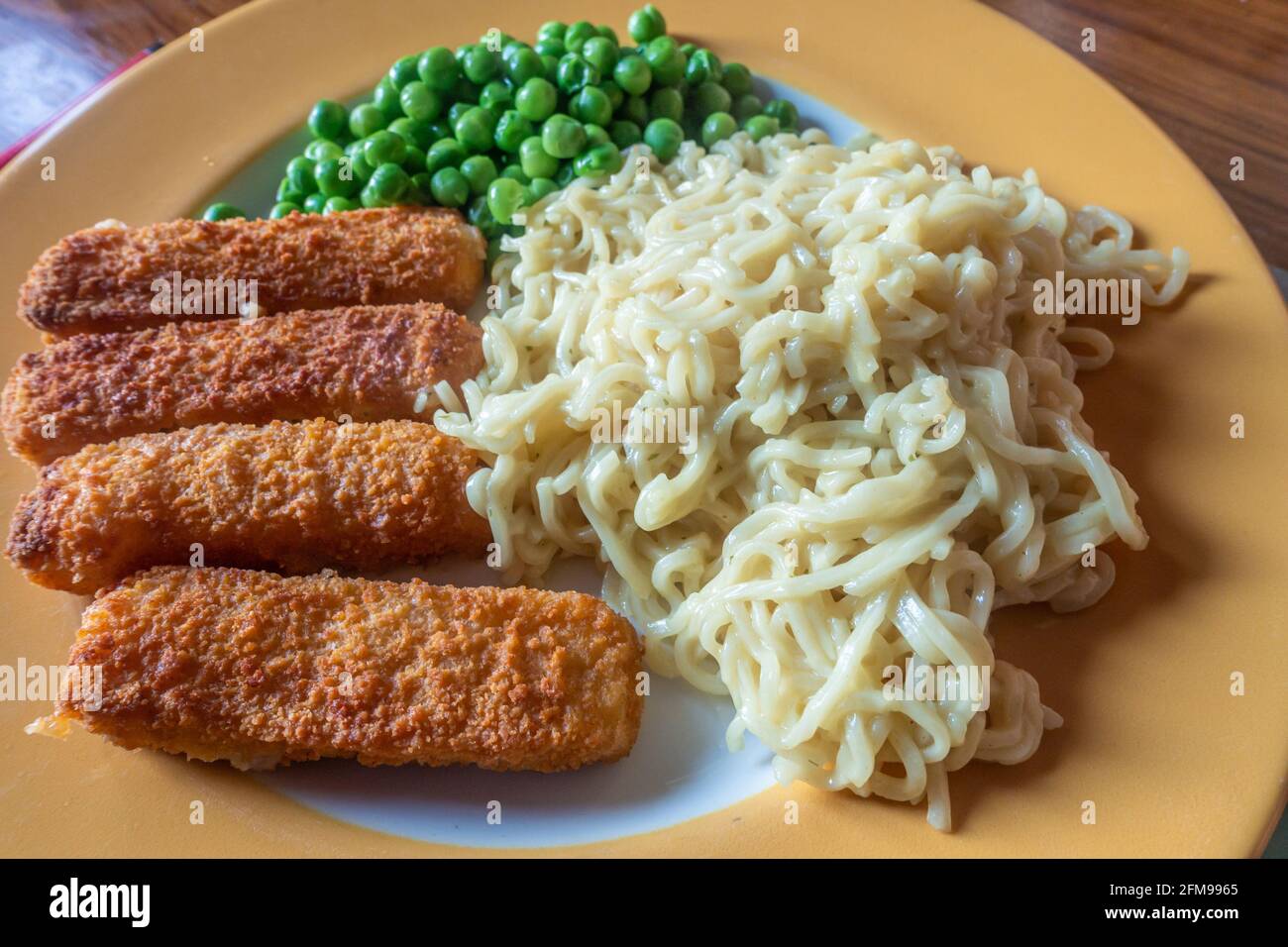 Un pasto veloce e facile composto da barrette di pesce, tagliatelle e piselli istantanei. Foto Stock