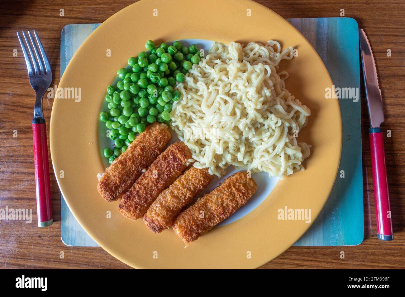 Un pasto veloce e facile composto da barrette di pesce, tagliatelle e piselli istantanei. Foto Stock