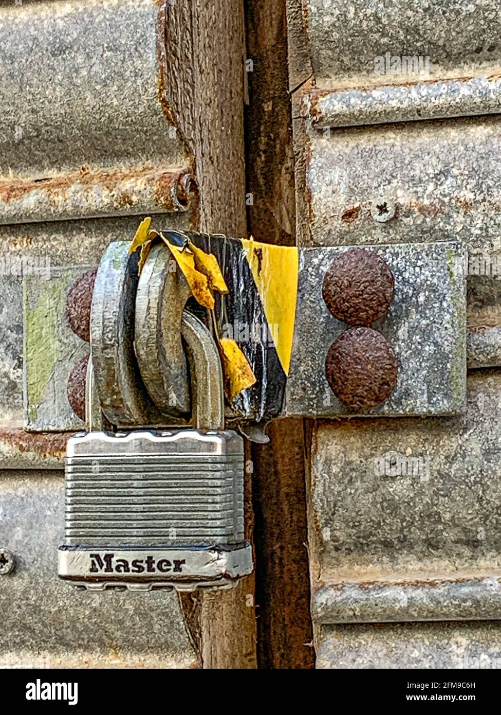 Lucchetto su porte metalliche, con nastro nero e giallo Foto Stock