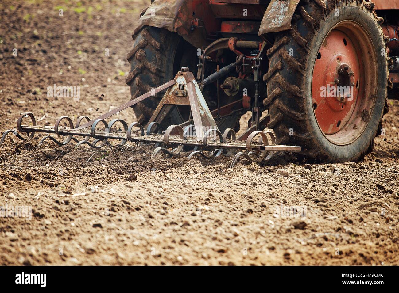 aratro trattore aratura la terra per piantare piante agricole. il coltivatore coltiva la terra in primavera per seminare semi. aratro di ferro del meccaniz Foto Stock