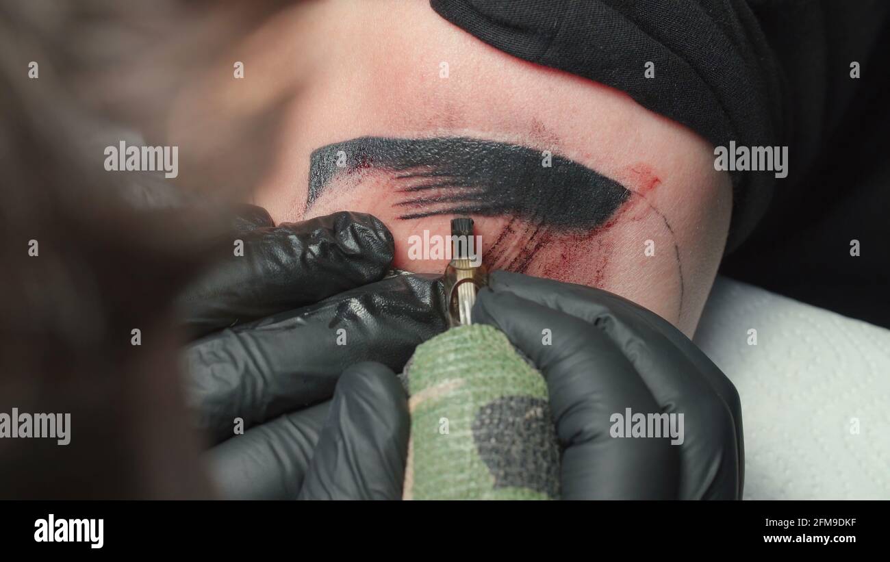 Sparare di tatuista uomo ottenere tatuaggio di serpente Foto Stock