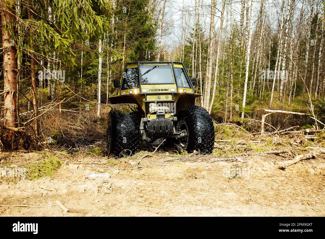 Un veicolo fuoristrada a trazione integrale attraversa la foresta attraverso il fango. Un SUV passabile con ruote grandi e gioco elevato. Speciale traspo Foto Stock