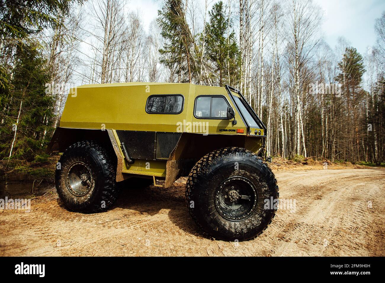 Un veicolo fuoristrada a trazione integrale attraversa la foresta attraverso il fango. Un SUV passabile con ruote grandi e gioco elevato. Speciale traspo Foto Stock