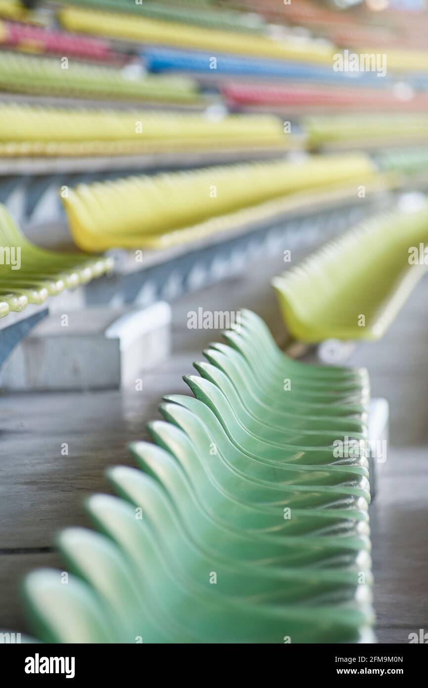 Gusci di sedili vuoti di colore pastello sulla tribuna in uno stadio sportivo Foto Stock