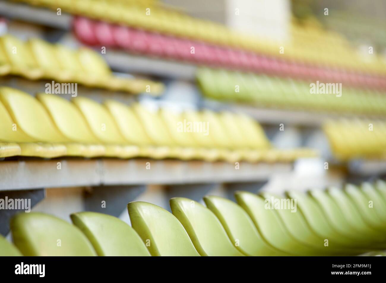 Gusci di sedili vuoti di colore pastello sulla tribuna in uno stadio sportivo Foto Stock