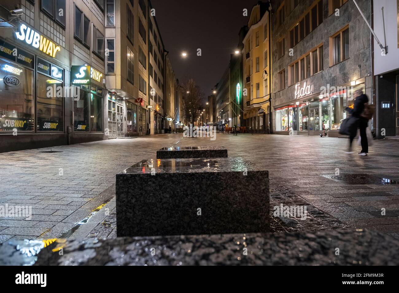 Helsinki / Finlandia - 5 MAGGIO 2021: Vista di una zona pedonale durante la sera delle piogge nel centro di Helsinki. Una donna che attraversa il telaio. Foto Stock
