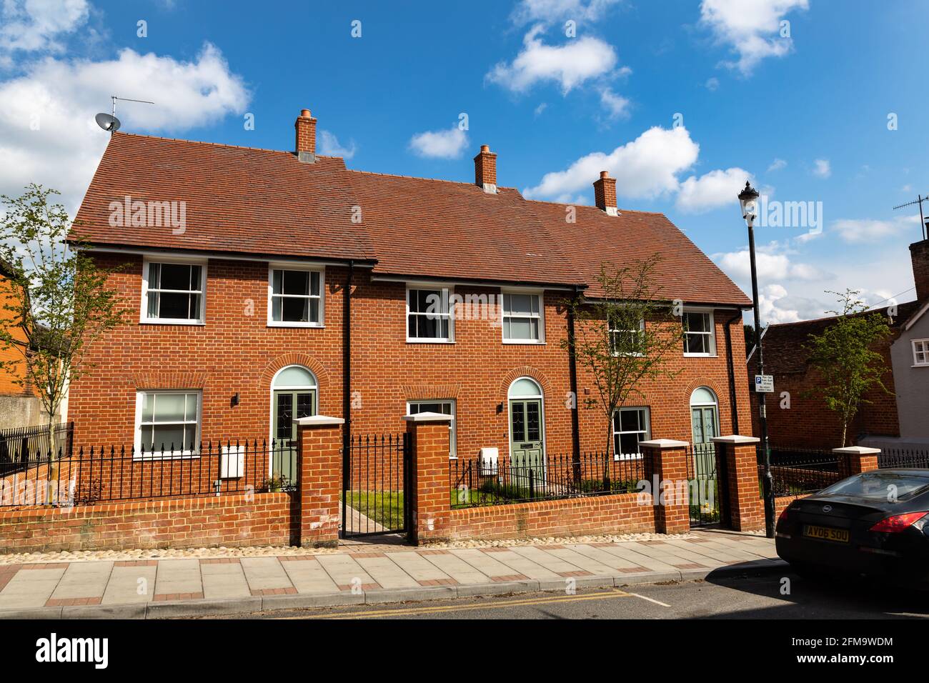Woodbridge, Suffolk, UK aprile 30 2021: Una fila di 3 case cittadine di recente costruzione nel centro di una trafficata città di mercato. All'esterno è parcheggiata un'auto sportiva Foto Stock