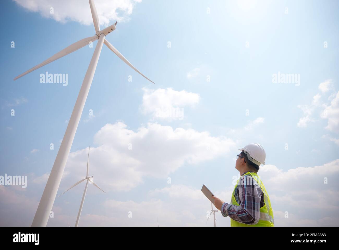 Un ingegnere di successo che utilizza una tavoletta con turbina eolica in background Foto Stock
