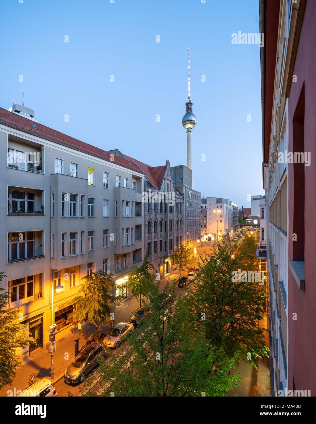 Berliner Strasse illuminato in serata con la torre della televisione di Berlino. Foto Stock
