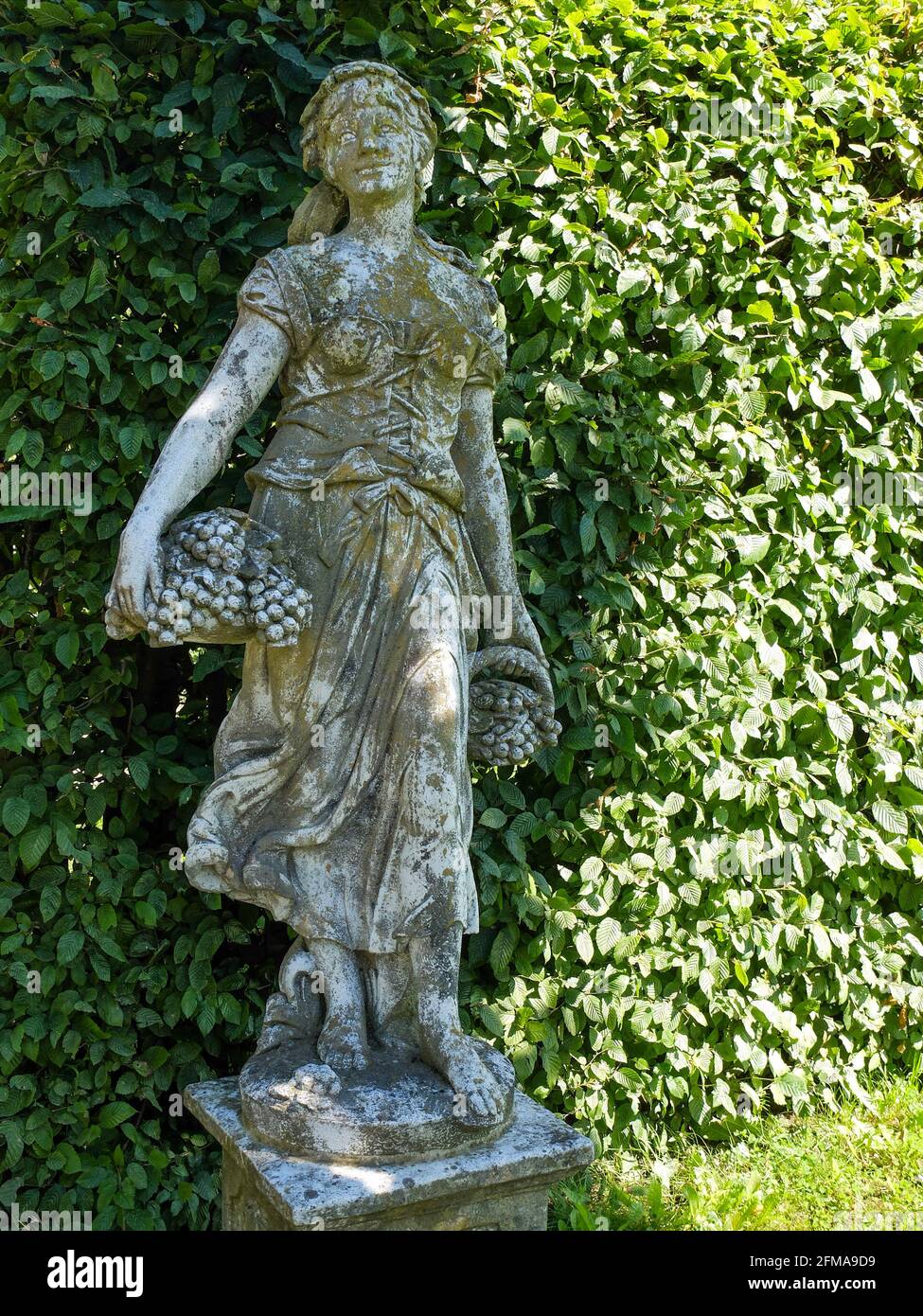 Scultura da giardino, giovane donna con cesto di frutta Foto Stock