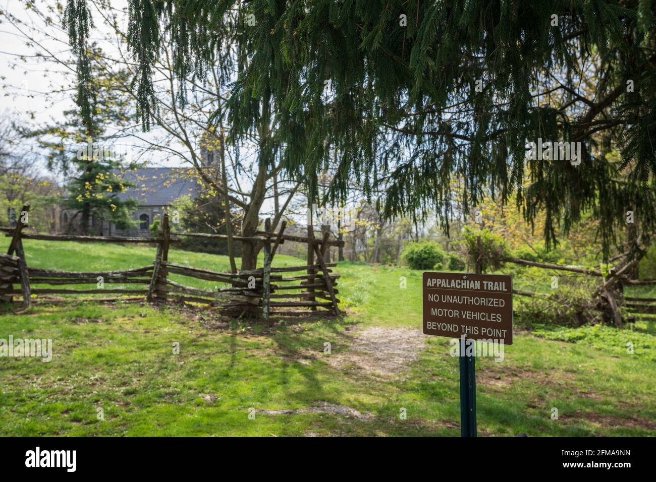 Il cartello Appalachian Trail dice "Nessun veicolo a motore non autorizzato al di là di questo punto' con la chiesa a fuoco morbido sullo sfondo Foto Stock