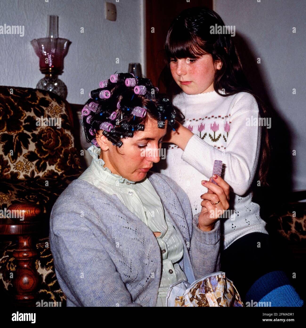 giovane ragazza che mette i rulli nei suoi capelli delle madri a casa 1980 inghilterra regno unito Foto Stock