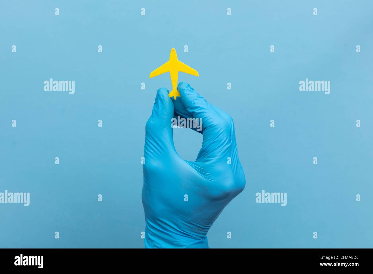 Una persona che indossa un guanto medico chirurgico che tiene un giallo aereo di viaggio Foto Stock