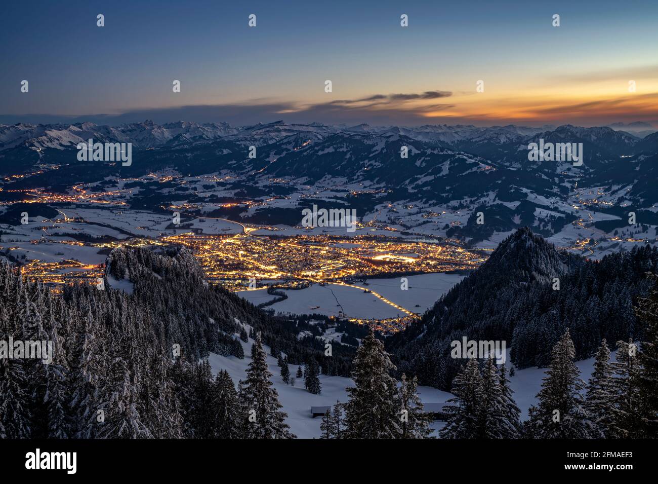Sonthofen, illuminato al tramonto in una fredda serata invernale, visto dal Grünten. Incorniciato dalle Alpi Allgäu innevate sotto un cielo blu. Baviera, Germania, Europa Foto Stock