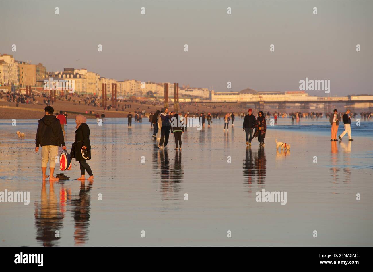 I beachgoers sulla spiaggia di Brighton durante una bassa marea, nel tardo pomeriggio, in primavera. Brighton, Susse, Inghilterra Foto Stock