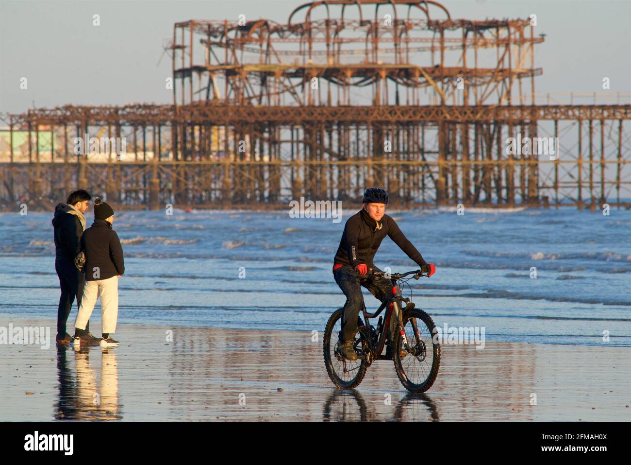 I beachgoers sulla spiaggia di Brighton durante una bassa marea, nel tardo pomeriggio, in primavera. Brighton, Sussex, Inghilterra. Pedalando sulla sabbia Foto Stock