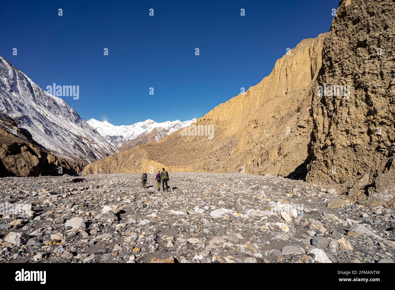 Escursionisti con facchini nel letto del fiume nella Valle di Lupra, Mustang, Nepal Foto Stock