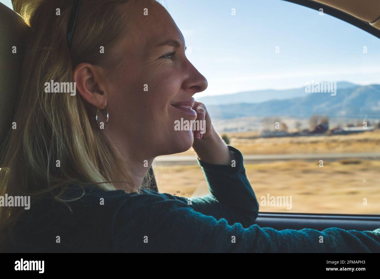 Donna sorridente che guida su strada nel deserto Foto Stock