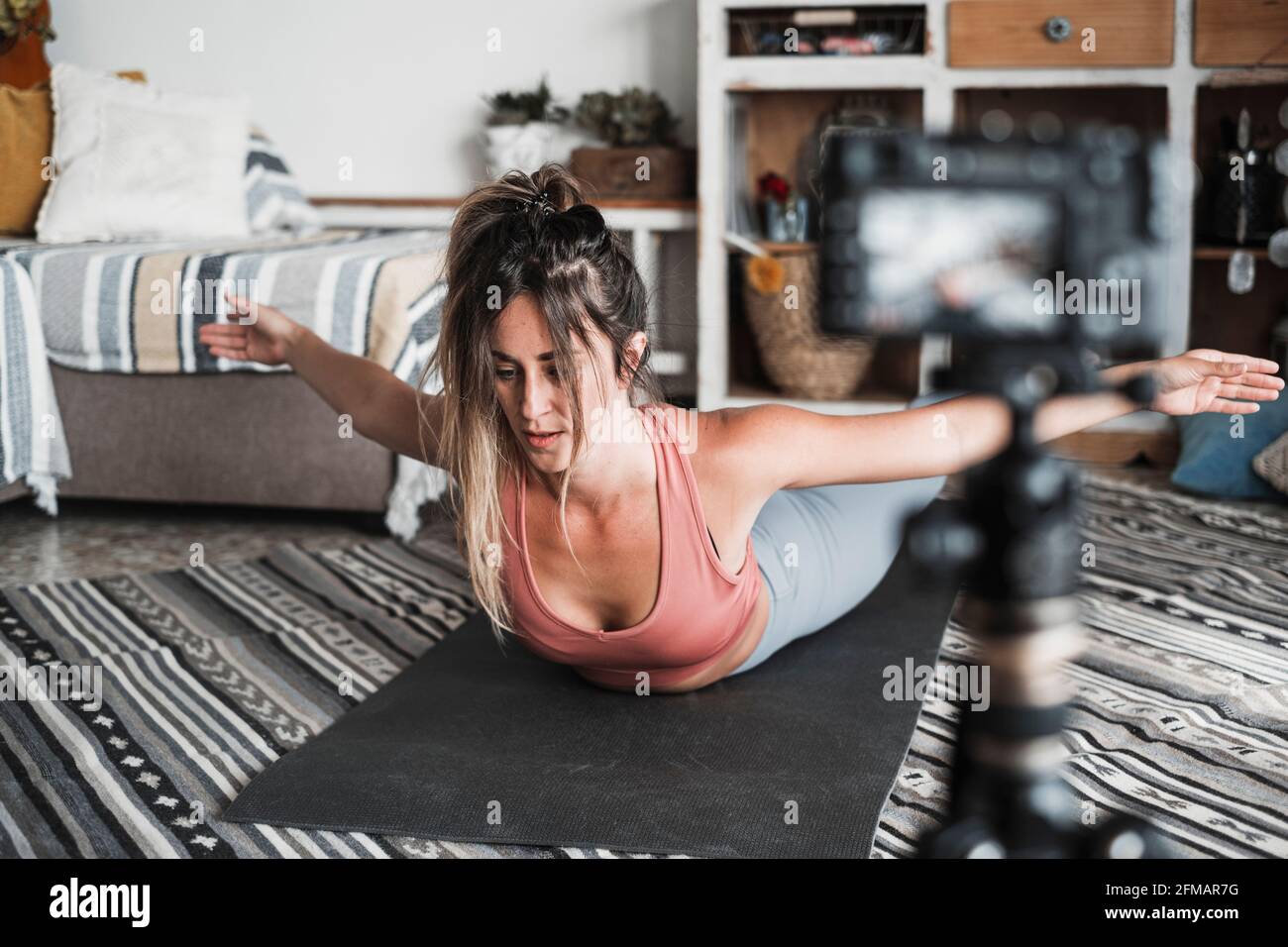 Giovane donna che si esercita a casa facendo pilates e registrando a. lei con fotocamera digitale per insegnare l'allenamento e produrre web classe - il concetto di gente sana di affari del creatore del soddisfare Foto Stock